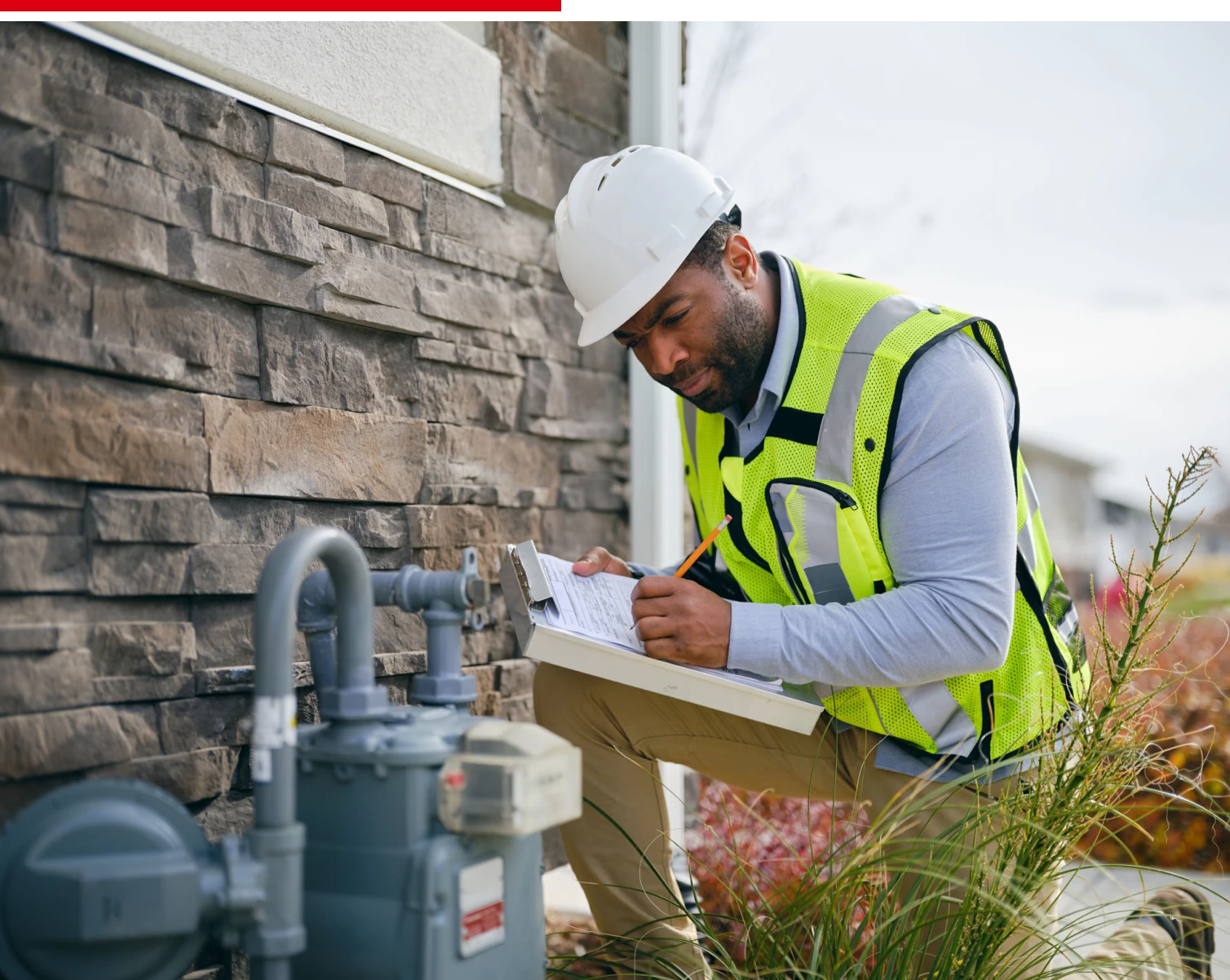 Utility worker inspecting gas meter outdoors
