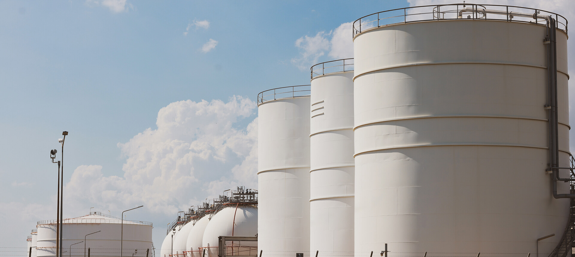 Large industrial storage tanks under blue sky.